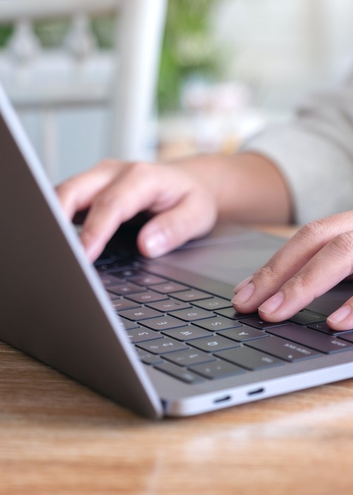 Closeup image of woman's hands using and typing on laptop keyboard on the table